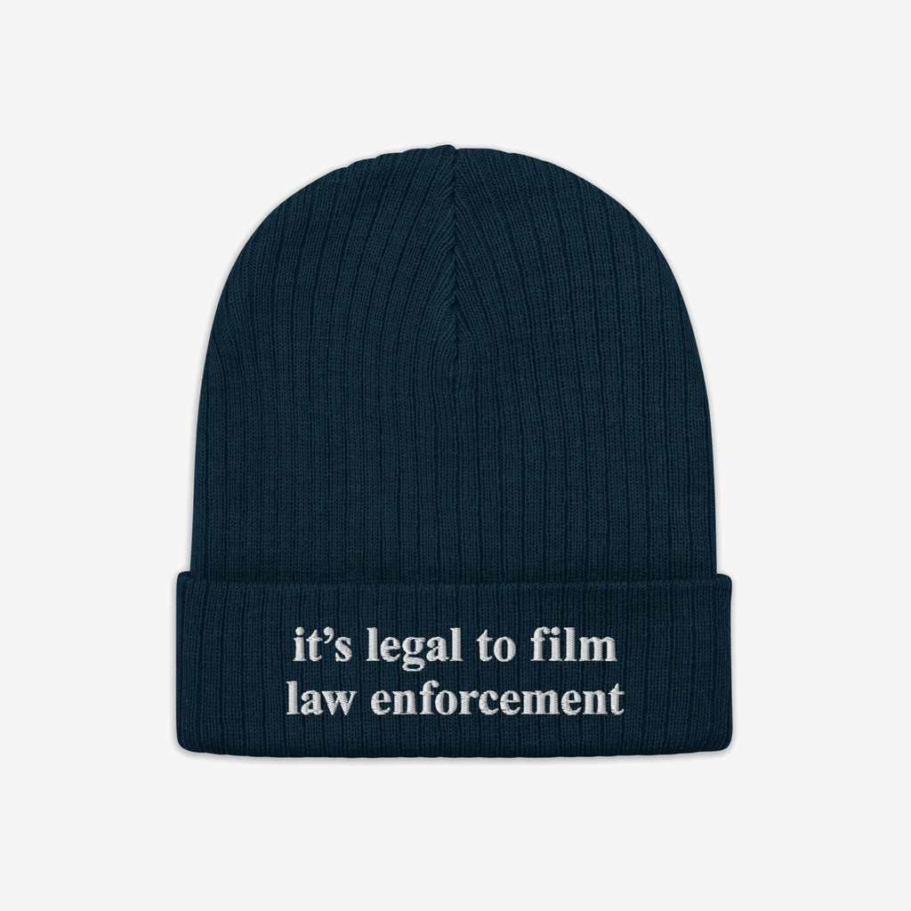 Film The Police Hat: A dark navy-blue ribbed knit beanie featuring white embroidered text it’s legal to film law enforcement on the cuff, symbolizing police accountability and rights awareness for cold weather activism.