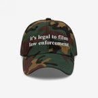 Camouflage-pattern baseball cap with white it’s legal to film law enforcement embroidery. The Film The Police Hat emphasizes rights awareness and police accountability, reflecting a commitment to social justice.