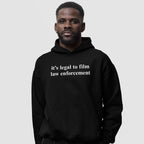 Adult male wearing a black Film The Police Hoodie & Sweatshirt with it’s legal to film law enforcement in white text, conveying a message of empowerment and social awareness.