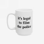Film The Police Mug features bold black serif-style text on a white ceramic surface, asserting “it’s legal to film the police,” available in two sizes, emphasizing protest energy and practicality.