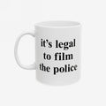 Film The Police Mug with bold black text on a plain white ceramic surface, reminding users it's legal to film police. Available in 11 oz. and 15 oz., microwave and dishwasher safe.