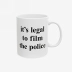 Film The Police Mug featuring bold black text, it's legal to film the police, on a white ceramic surface. Available in 11 oz. and 15 oz., it's dishwasher and microwave safe.
