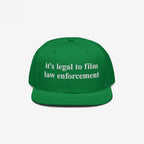 Film The Police Hat featuring bold white embroidered text, it’s legal to film law enforcement, on a green flat-brimmed cap, promoting police accountability and awareness of your rights.