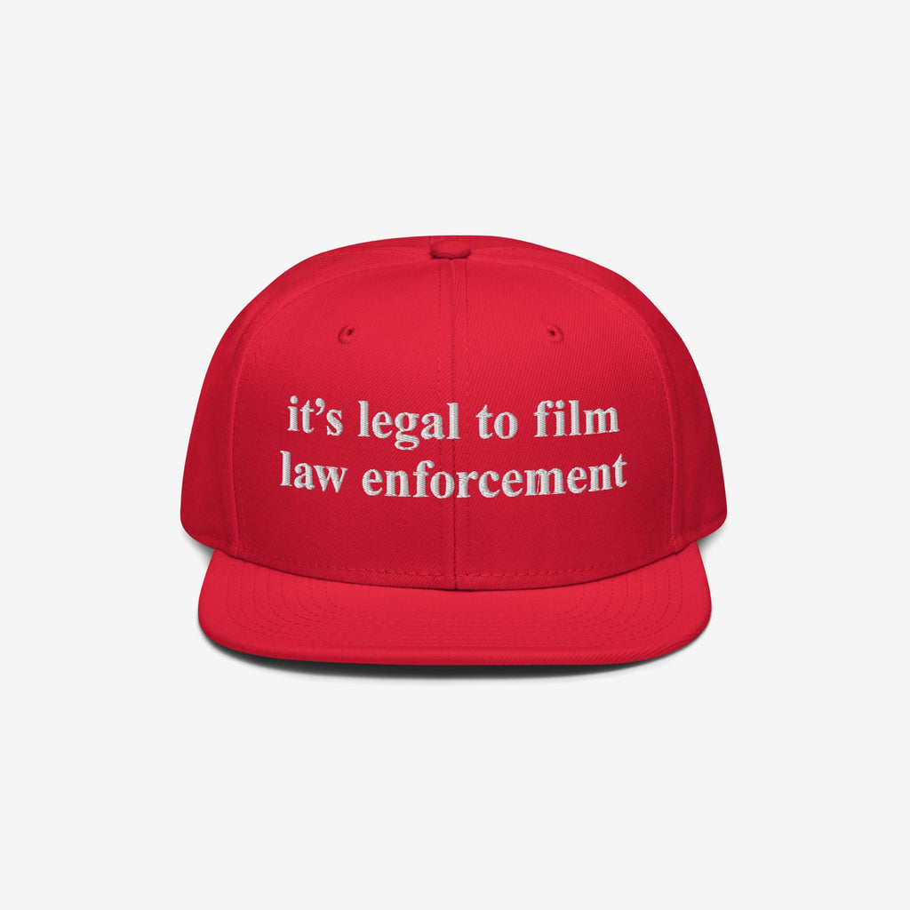 Film The Police Hat with a bright red, flat-brimmed design features white embroidered text stating it’s legal to film law enforcement, emphasizing police accountability and rights awareness.