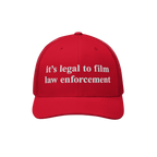 Red mesh-back trucker cap with white embroidered it’s legal to film law enforcement text. The Film The Police Hat embodies 