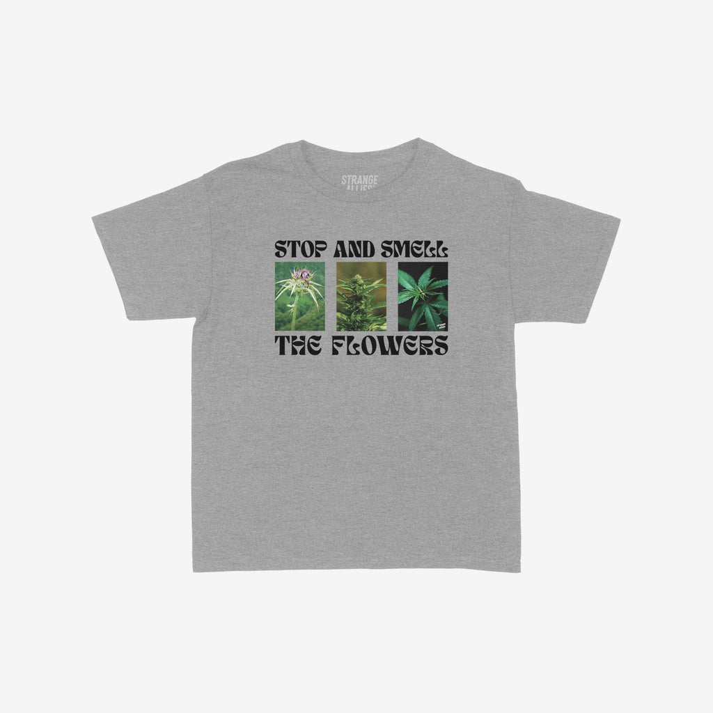 Flowers Women's Baby Tee featuring STOP AND SMELL THE FLOWERS text with three cannabis plant photos, capturing a playful blend of self-care and botanical appreciation. Ideal for enthusiasts embracing nature's calming elements.