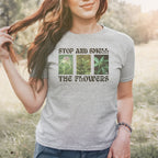 The Flowers Women's Baby Tee features a playful three-panel cannabis graphic with the slogan “STOP AND SMELL THE FLOWERS,” blending humor and botanical appreciation for those who value self-care and individuality.