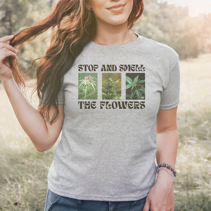 The Flowers Women's Baby Tee features a playful three-panel cannabis graphic with the slogan “STOP AND SMELL THE FLOWERS,” blending humor and botanical appreciation for those who value self-care and individuality.