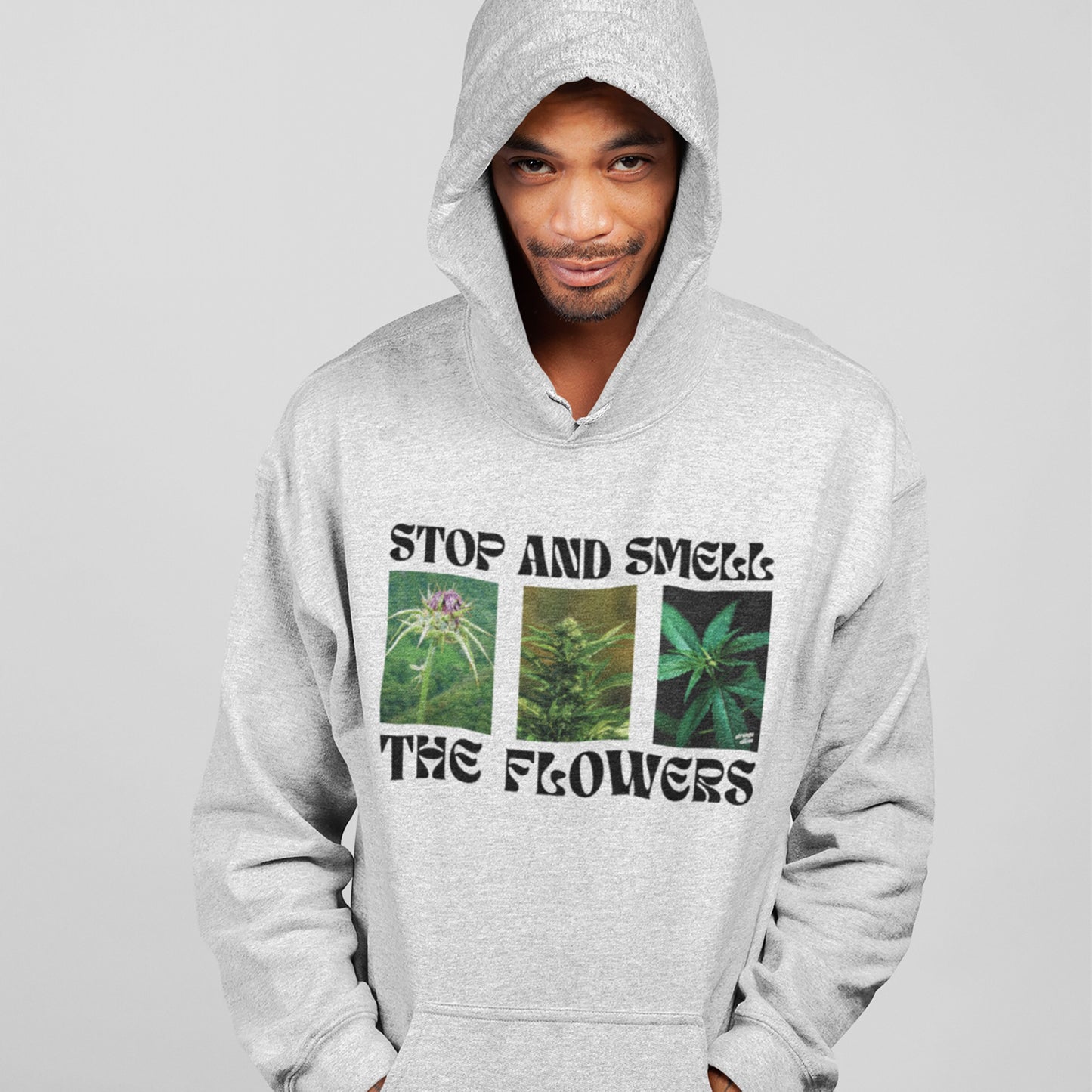 Adult male wearing the Flowers Hoodie & Sweatshirt, featuring cannabis plant graphics and the phrase “STOP AND SMELL THE FLOWERS.” The design conveys a bold, unapologetic celebration of cannabis culture.