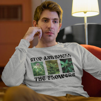 Young man in cozy lounge wearing the Flowers T-shirt with cannabis plant images and STOP AND SMELL THE FLOWERS slogan, embodying humor and laid-back style.