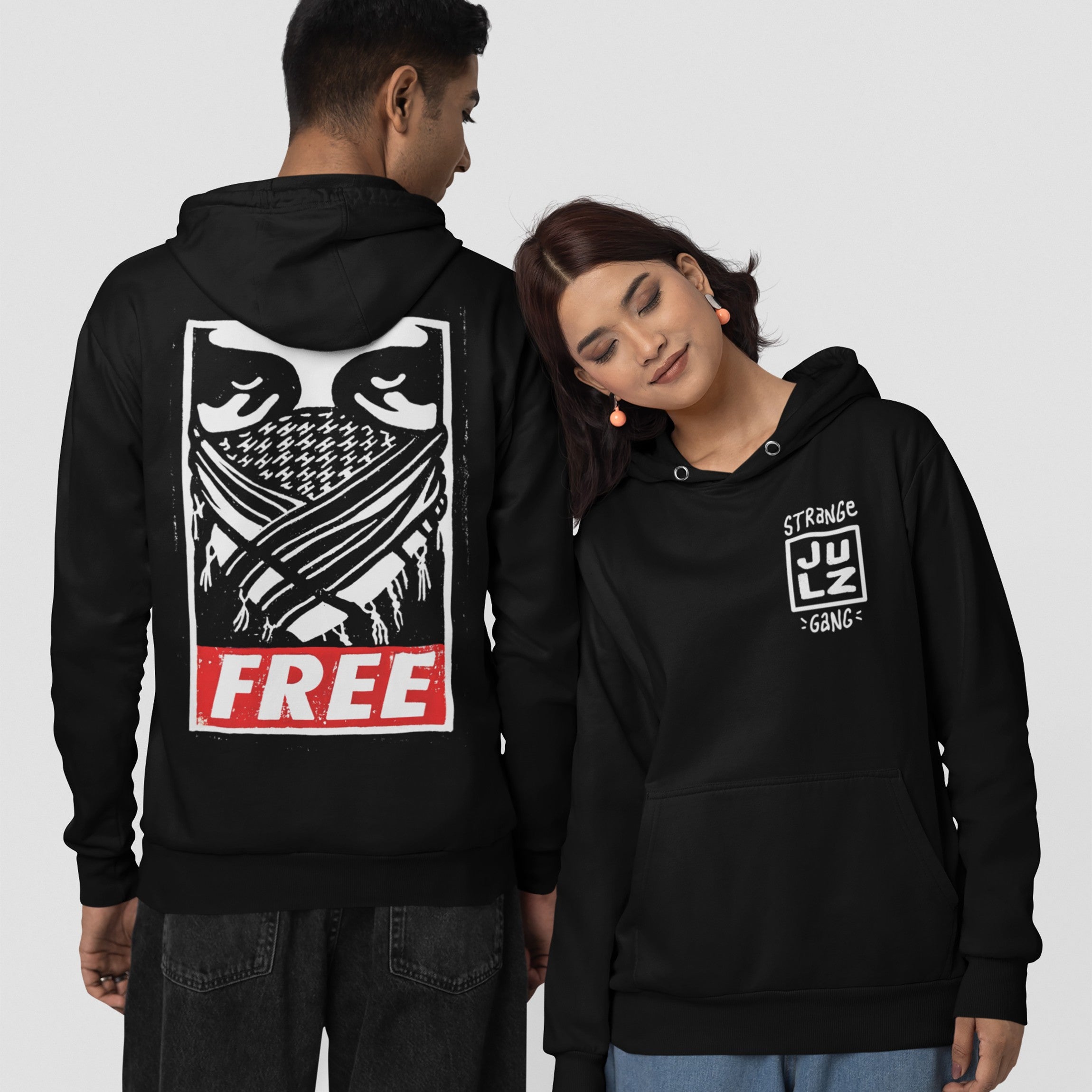 Two people model the Free Palestine JULZ Hoodie, featuring a masked face graphic and FREE text on the back, and a small front logo, symbolizing activism and solidarity.