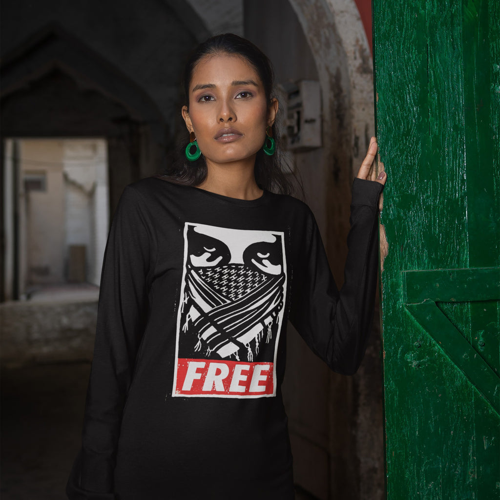 Woman in corridor wearing Free Palestine JULZ T-shirt with graphic eyes and FREE text, leaning on a green door, embodying a message aligned with activism and equality.