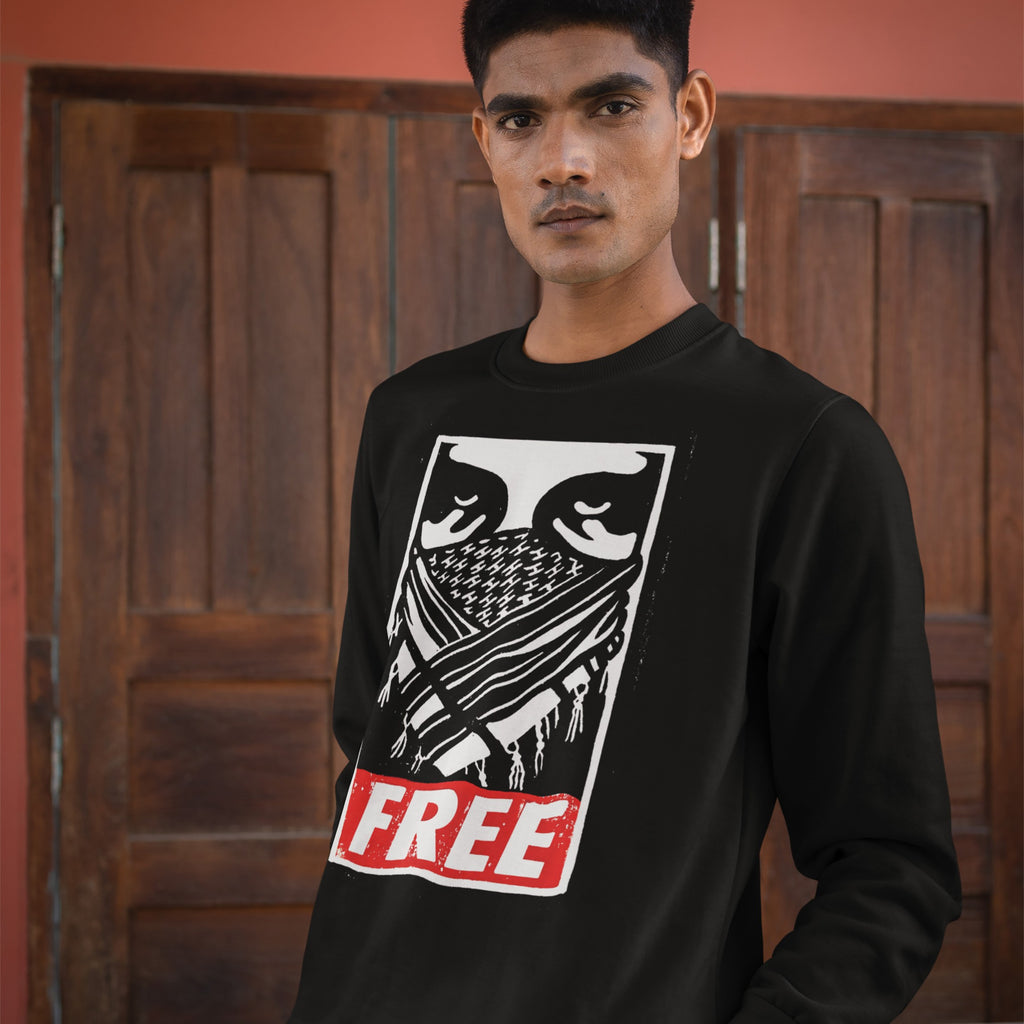 Young man wearing the Free Palestine JULZ Sweatshirt, featuring bold graphic eyes, a criss-cross pattern, and FREE lettering, symbolizing solidarity with Palestinian freedom.