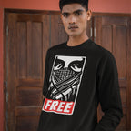 Young man wearing the Free Palestine JULZ Sweatshirt, featuring bold graphic eyes, a criss-cross pattern, and FREE lettering, symbolizing solidarity with Palestinian freedom.