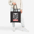 Person holding the Free Palestine JULZ Tote Bag, featuring block-print eyes and FREE on a black canvas. A collaboration with artist JULZ, symbolizing support for Palestinian freedom.
