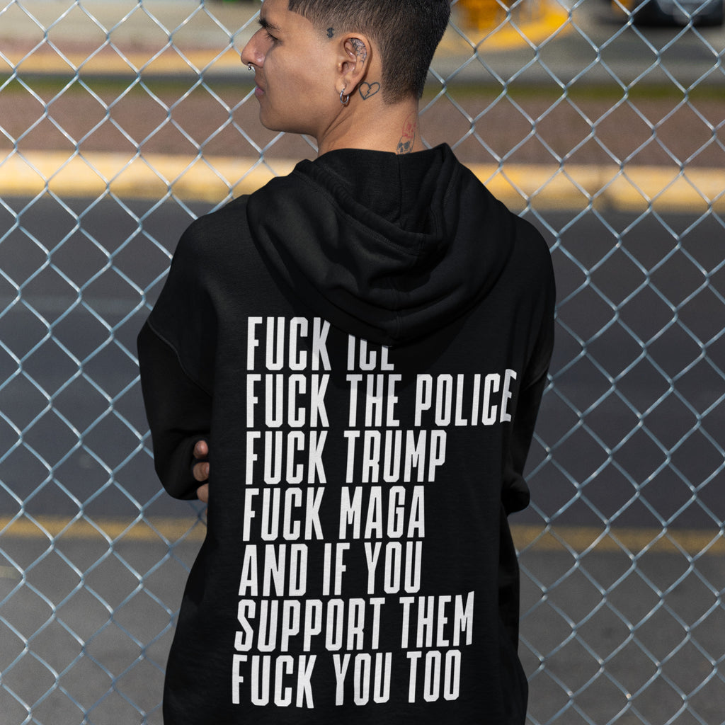 Back view of a person wearing the Fuck 'Em All Back Print Shirt, featuring bold protest text against ICE, police, and Trump. Visible are tattoos behind their ear and neck, and facial piercings.