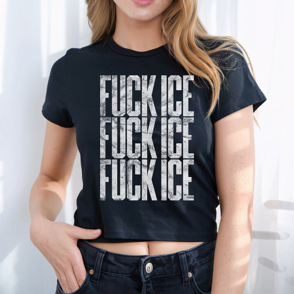 Young woman in a black cropped FUCK ICE baby tee with distressed white lettering, embodying bold activism and street style, hand casually hooked into her dark jeans.