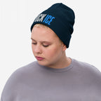 Person wearing a dark navy FUCK ICE knit beanie with bold white and blue 3D embroidery. The beanie is paired with a plain grayish-lavender sweatshirt, highlighting a powerful statement against injustice.
