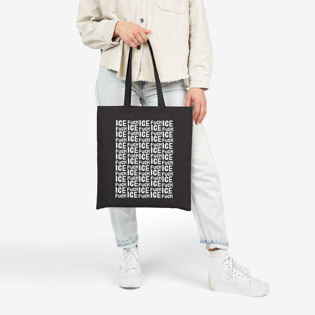 Person holding a black Fuck ICE Pattern Tote Bag, featuring bold white text pattern. Paired with casual light-wash jeans, cream shacket, and white sneakers, symbolizing protest and advocacy through everyday style.