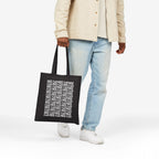 Fuck ICE Pattern Tote Bag held by a casually dressed person, showcasing its bold white text design against black canvas, symbolizing a stance against ICE, supporting equality and human rights advocacy.