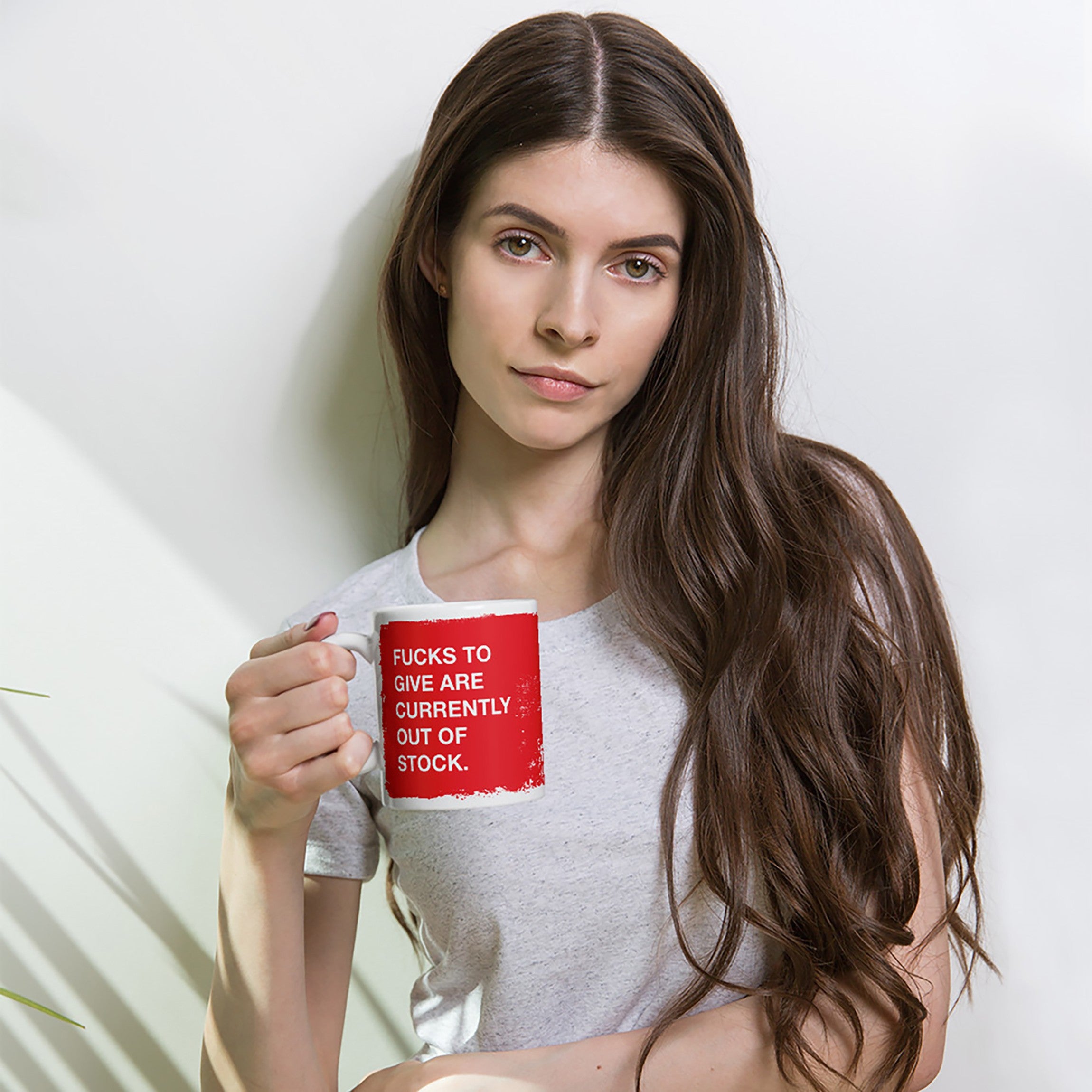 Young woman holds a Fucks To Give Mug with bold text, embodying a message of unapologetic honesty. This ceramic piece serves as a humorous declaration of mood, ideal for those low on patience.