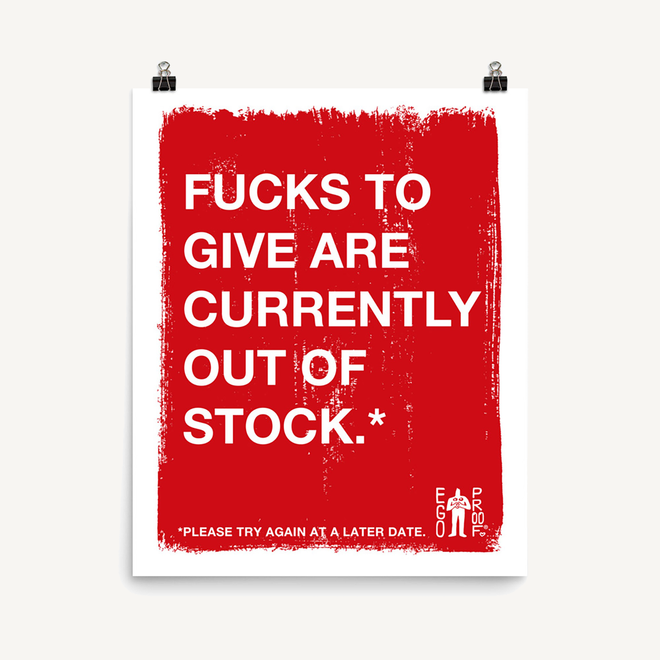 Fucks To Give Giclée Print with bold white text on distressed red background humorously declares emotional exhaustion. Displayed above a light-wood console with black accessories, embodying a modern, playful aesthetic.