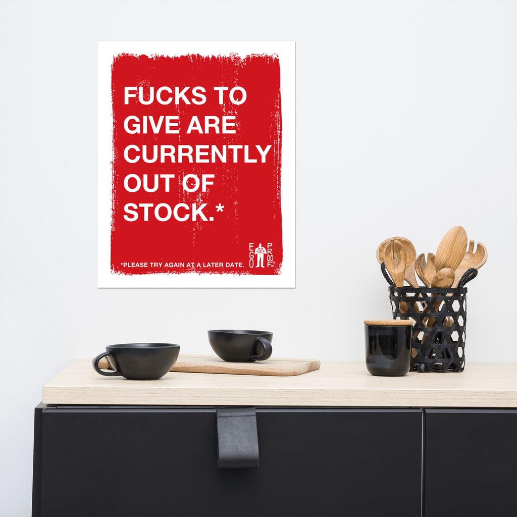 Fucks To Give Giclée Print with bold white text on distressed red background humorously declares emotional exhaustion. Displayed above a light-wood console with black accessories, embodying a modern, playful aesthetic.