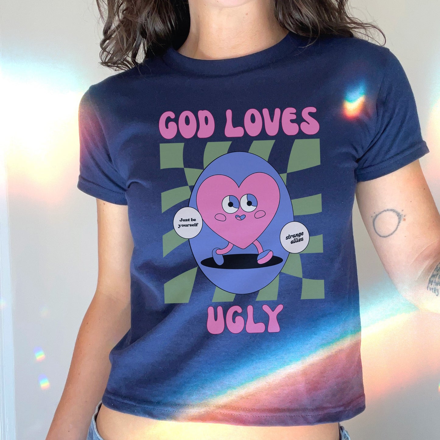 God Loves Ugly Women's Baby Tee featuring a retro cartoon heart with just be yourself and strange allies speech bubbles, celebrating uniqueness and individuality. Perfect for expressing nonconformity and personal authenticity.