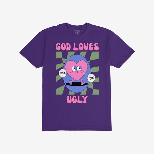 God Loves Ugly T-shirt featuring a cartoonish pink heart character with affirmations, embodying a bold, inclusive message of self-worth, surrounded by vintage comic book style on a purple tee.