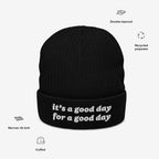 The Good Day Hat is a black, cuffed knit beanie with white embroidered text, it's a good day for a good day, featuring a narrow rib knit design made from recycled polyester.