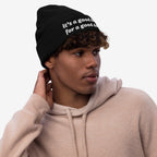 Young man wearing the Good Day Hat, a black knit beanie embroidered with “it’s a good day for a good day,” embodying positivity and mental health advocacy. He's gazing thoughtfully to the side.