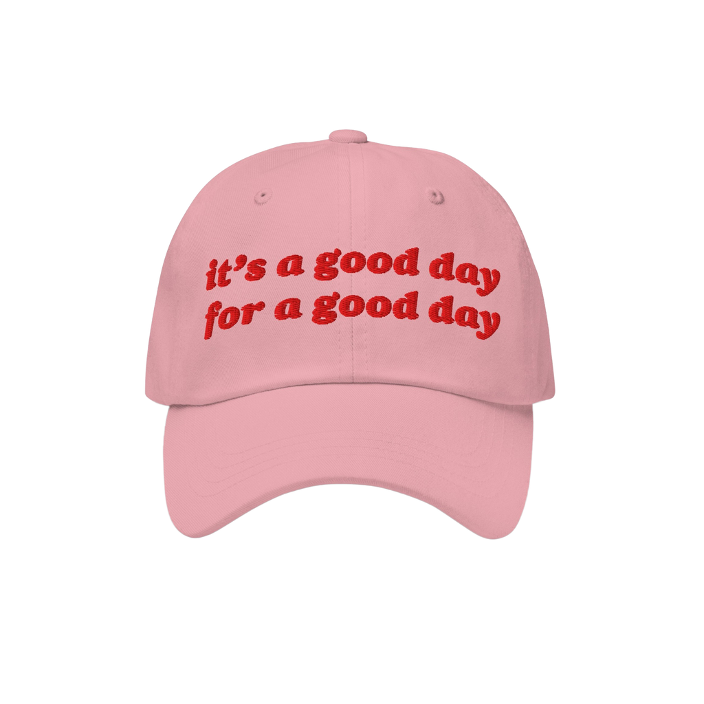 The Good Day Hat features uplifting red embroidery stating, “it’s a good day for a good day,” on a light pink baseball 
