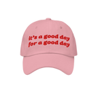 The Good Day Hat features uplifting red embroidery stating, “it’s a good day for a good day,” on a light pink baseball 