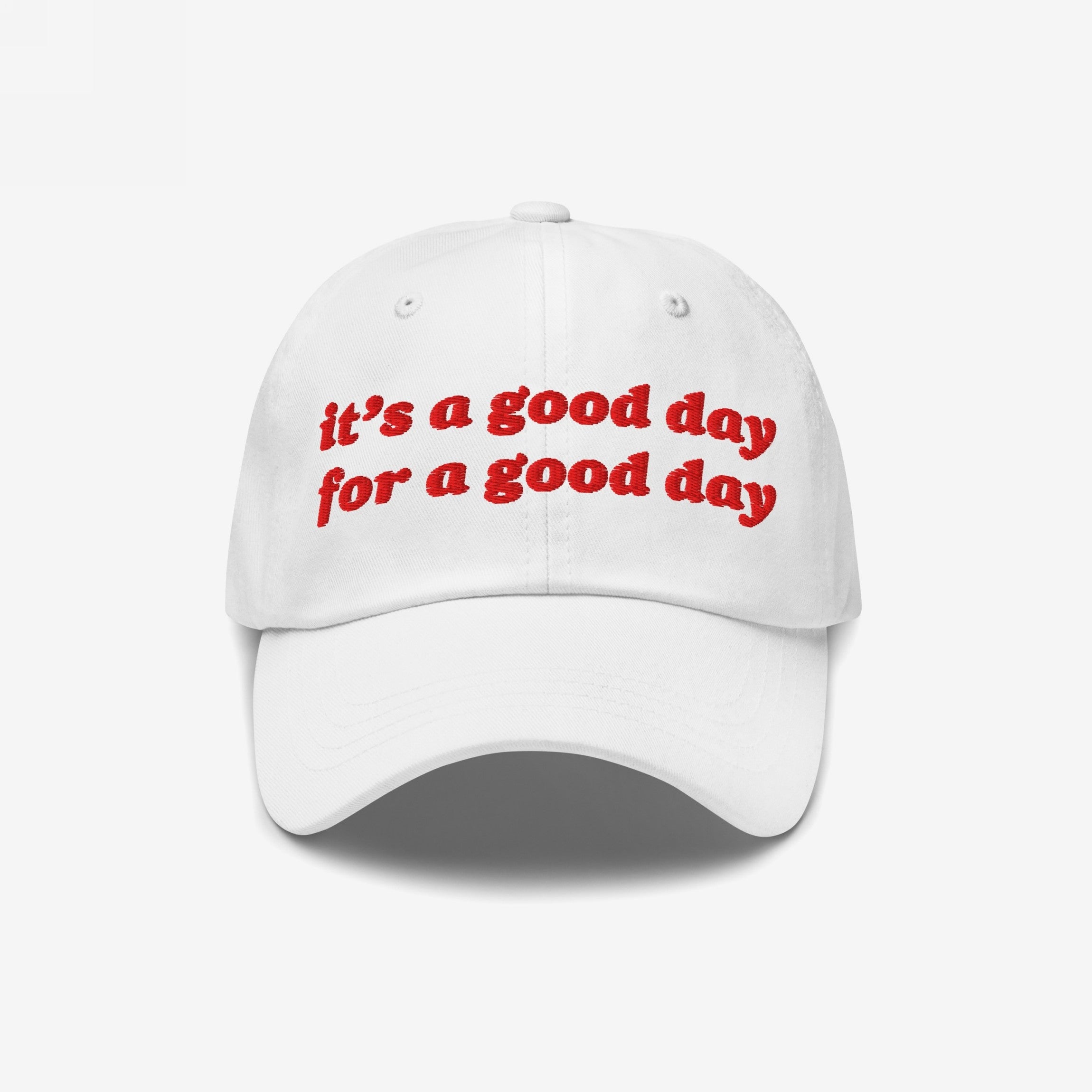The Good Day Hat features red embroidered lettering, it's a good day for a good day, on a white baseball-style cap, promoting positivity and mental health awareness.