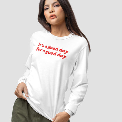 Good Day T-shirt features a white long-sleeved design with bold red slogan, “it’s a good day for a good day,” embodying optimistic vibes. Modeled by a female, emphasizing positivity and inclusivity.