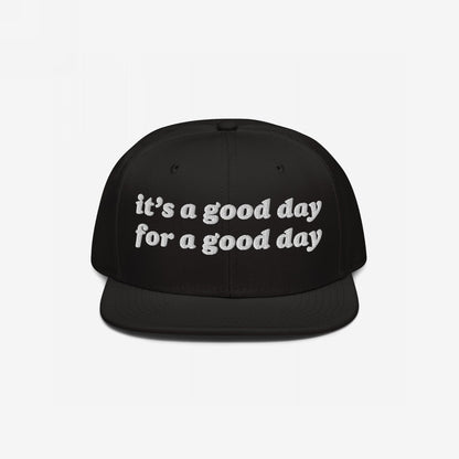 Black flat-brim cap with white embroidered text: “it’s a good day for a good day.” This Good Day Hat combines retro style with positive vibes, perfect for advocating mental health and optimism.
