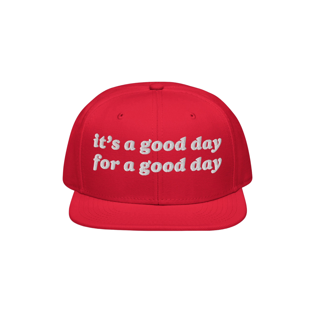 The Good Day Hat features white embroidered text stating it’s a good day for a good day on a red, flat-brim cap, promoting 