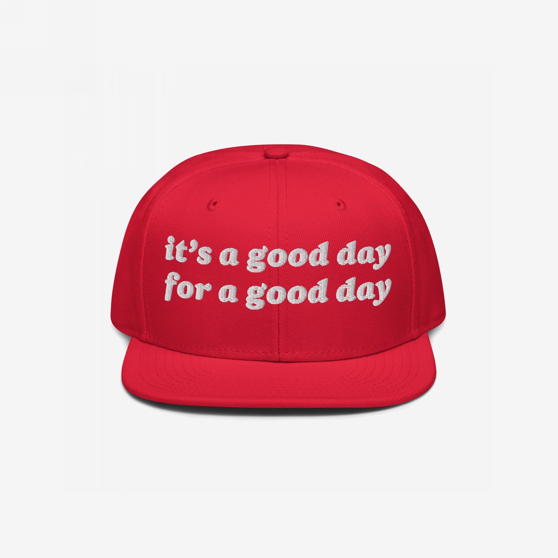 The Good Day Hat features bright red, flat-brim snapback style with white embroidered text, promoting optimism and mental health advocacy through its “it’s a good day for a good day” message.