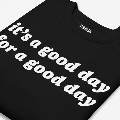 Folded black T-shirt with bold white text on front: “it’s a good day for a good day.” Neck label reads “STRANGE.” Part of the Good Day Hoodie & Sweatshirt collection, promoting optimism and positivity.