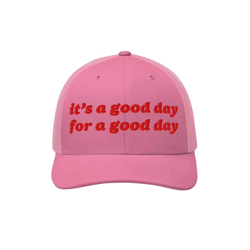 Good Day Hat: A pink trucker-style cap with mesh back, featuring bold red embroidery stating “It’s a good day for a good 