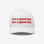 Good Day Hat: A white trucker-style cap with red embroidered text, it’s a good day for a good day, mesh back, and curved brim, promoting positivity and mental health awareness.
