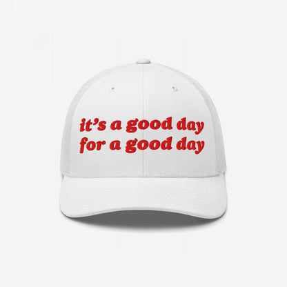 Good Day Hat: white trucker-style cap with red embroidered uplifting text, curved brim, and mesh back. Ideal for promoting positive vibes and supporting mental health advocacy.