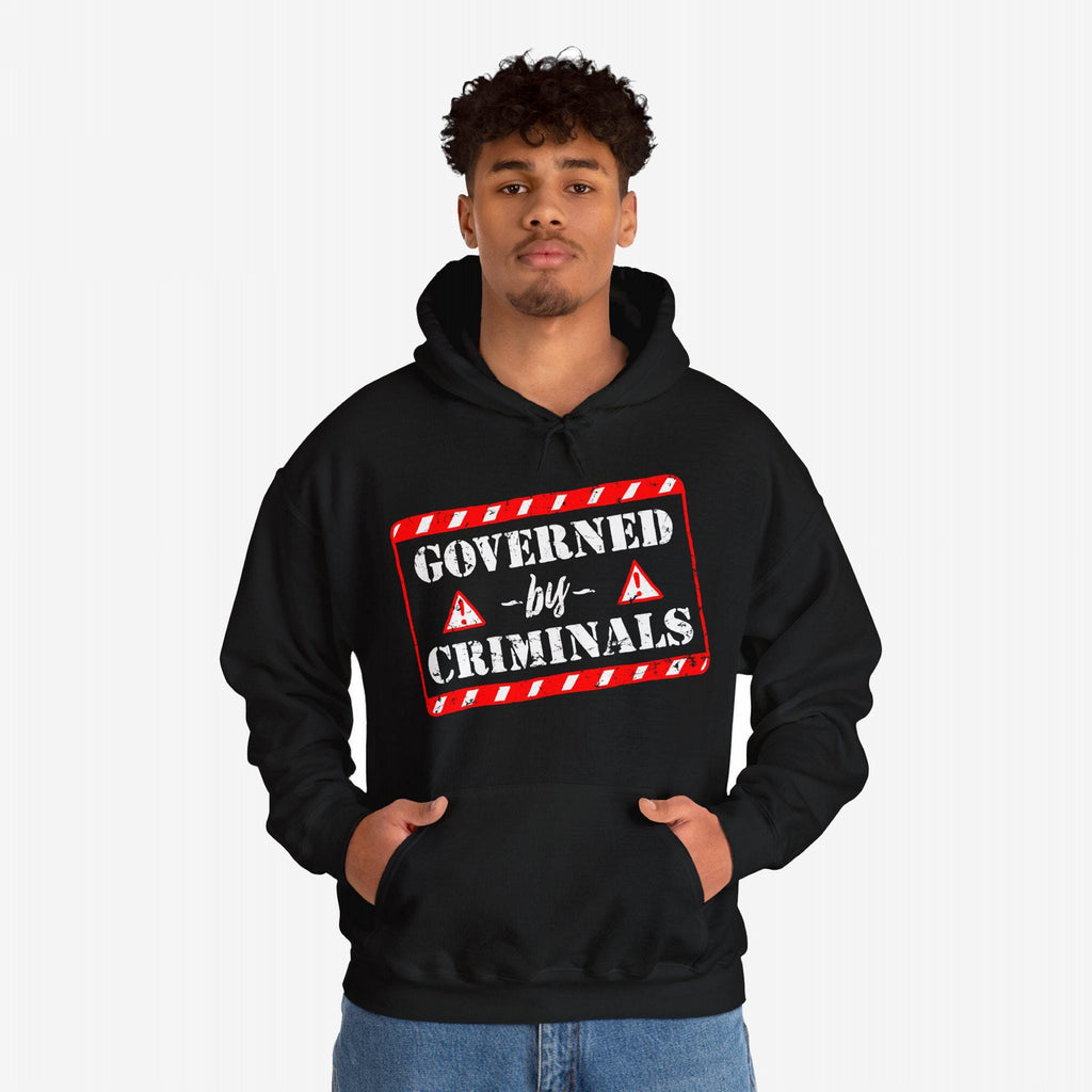 Person wearing Governed By Criminals hoodie featuring a bold red-and-white warning label graphic, symbolizing resistance against political corruption. Ideal for those challenging systems, supporting SPLC.