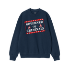 Navy-blue crewneck sweatshirt with Governed By Criminals in bold stencil text and caution-triangle icons, conveying a bold po