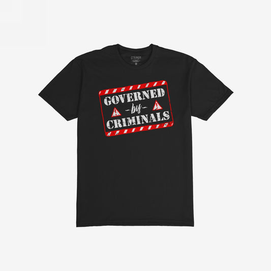 Governed By Criminals T-shirt featuring a bold, distressed red-and-white graphic with stencil lettering, framed by red stripes and warning triangles, conveying a powerful message against corruption and elite power.
