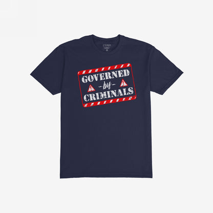 Navy-blue Governed By Criminals T-shirt with distressed graphic resembling a warning stamp, featuring bold white letters and red hazard stripes, challenging corruption and power dynamics. Ideal for protests and conversations.
