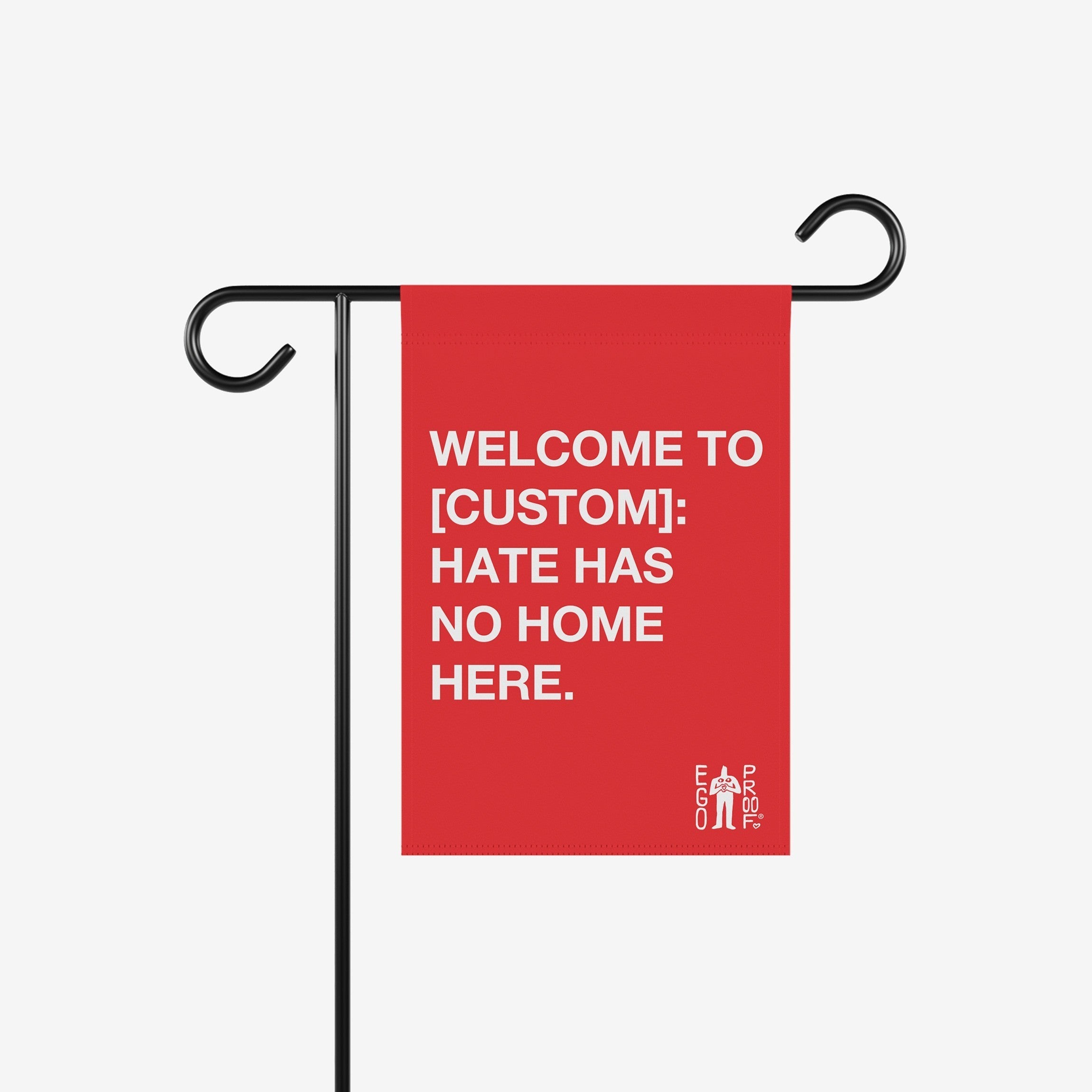 Custom Hate Has No Home Here Garden Flag hanging on a black metal stand, featuring bold white text promoting unity and inclusion. Includes customizable city name space, embodying anti-hate values.
