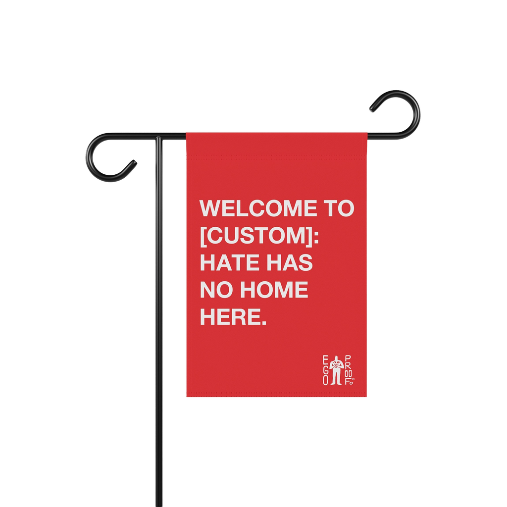 Custom Hate Has No Home Here Garden Flag hanging on a black metal stand, featuring bold white text promoting unity and inclus