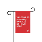 Custom Hate Has No Home Here Garden Flag hanging on a black metal stand, featuring bold white text promoting unity and inclus