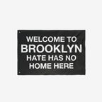 Black flag with bold white text: WELCOME TO BROOKLYN HATE HAS NO HOME HERE. The Custom Hate Has No Home Here Flag promotes justice and equality, customizable for your city or neighborhood.